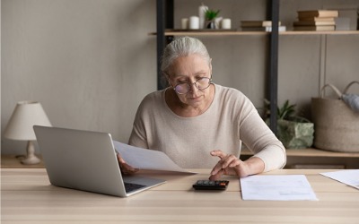 woman using calculator at desk with laptop